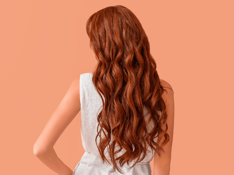 mulher de costas com cabelo ruivo em camadas modelado com babyliss.